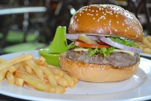 verse smakelijke rundvleesburger en frietjes geserveerd op houten dienblad op tafel in fastfoodwinkel foto