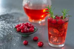 glas verse cranberry vruchtensap bio biologische sap gezondheid met rozemarijn, kruik, op een grijze leisteen achtergrond foto