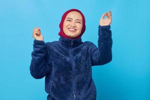 portret van mooie jonge aziatische vrouw die gelukkig en vrolijk danst op blauwe achtergrond foto