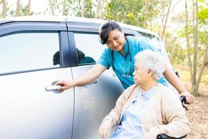 hulp en ondersteuning aziatische senior of oudere oude dame vrouw patiënt zittend op rolstoel voorbereiden om naar haar auto te gaan, gezond sterk medisch concept. foto