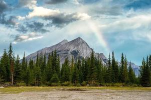 mount rundle met pijnbomen en regenboog in de blauwe lucht foto