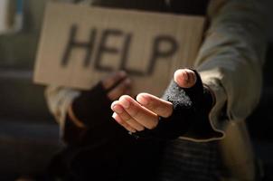 een dakloze man die om hulp smeekt. vraag om een muntstuk van menselijke barmhartigheid op een houten vloer in een openbare gang. arme daklozen in de stad sociale problemen financiën en huisvesting foto