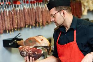 slager met een stuk ham in zijn hand foto