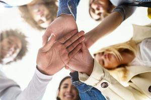 multi-etnische groep mensen die hun handen in elkaar slaan. foto