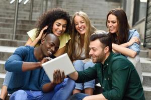 multi-etnische groep jongeren die naar een tabletcomputer kijken foto