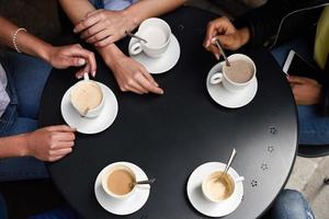 bovenaanzicht van handen met koffiekopjes in een stedelijk café. foto