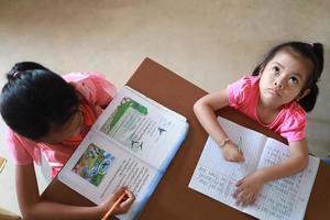 een schattig Aziatisch meisje dat overdag huiswerk maakt in haar huis foto