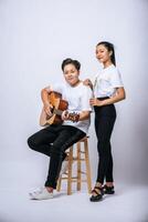 twee jonge vrouwen zaten op een stoel en speelden gitaar. foto