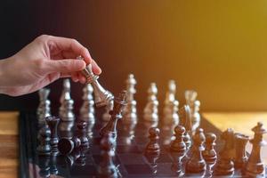 hand van zakenman die schaakbordspel beweegt in competitiesuccesspel foto