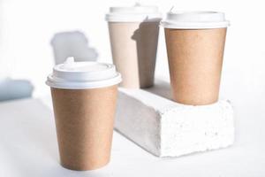 kopjes koffie to go gemaakt van eco-materiaal, karton en herbruikbare plastic deksels. take away koffie en drankjes concept. minimale stijl. foto