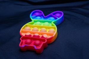 kleurrijk pop-it-speelgoed in de vorm van een konijn op een zwarte achtergrond.