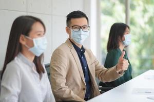 zakelijke werknemers die tijdens het werk op kantoor een masker dragen om de hygiëne te behouden, volgen het bedrijfsbeleid. preventief tijdens de periode van epidemie van coronavirus of covid19.