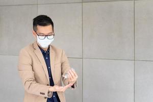zakenman die een masker draagt en persoonlijk ontsmettingsmiddel gebruikt om zijn hand op kantoor schoon te maken om de hygiëne te behouden. preventief tijdens de periode van epidemie van coronavirus of covid19.