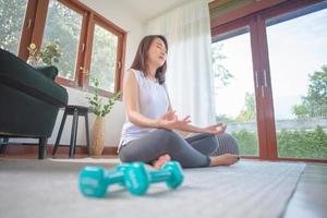 mooie aziatische vrouw blijf kalm en mediteert terwijl ze thuis yoga beoefent voor een gezonde trendlevensstijl