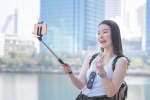 mooie aziatische vrouw geniet van het gebruik van video-oproeptechnologie op een smartphone in het centrum van de stad. vakantie reizen in de zomer.