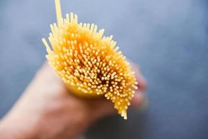 man met rauwe spaghetti italiaanse pasta ongekookte spaghetti geel lang klaar om te koken in het restaurant italiaans eten en menu foto