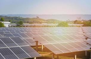 weergave van zonnepanelen in het zonnepark met groene boom en zonlicht reflecteren - zonnecel-energie of hernieuwbare energieconcept foto