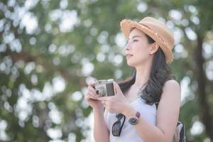 mooie aziatische solo-toeristische vrouw geniet van het nemen van foto's door retro camera op toeristische bezienswaardigheden. vakantie reizen in de zomer. foto