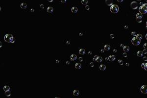 transparante bubbels zeep patroon overlay abstracte deeltjes spatten van water op zwart. foto