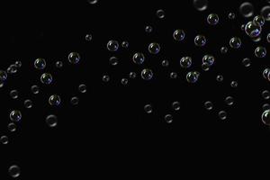 transparante bubbels zeep patroon overlay abstracte deeltjes spatten van water op zwart. foto