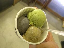 ijs groen smaak bevroren dessert patroon in zwarte kop hand vasthouden op hout. foto