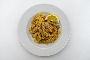 Italiaanse fusilli pasta met tonijn en citroen in een witte schotel foto