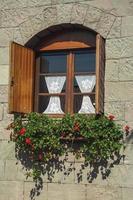 glazen raam met bloemen en houten luiken in een landhuis met stenen muur in de buurt van bento goncalves. een vriendelijk plattelandsstadje in Zuid-Brazilië, beroemd om zijn wijnproductie. foto