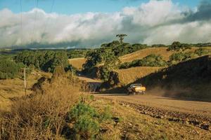 pick-up op een onverharde weg door landelijke laaglanden met droge heuvels en bomen genaamd pampa's in de buurt van cambara do sul. een klein stadje in het zuiden van Brazilië met verbazingwekkende natuurlijke toeristische attracties. foto