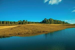 blauw watermeer op landschap van landelijke laaglanden genaamd pampa's met droge struiken die de heuvels bedekken in de buurt van cambara do sul. een klein stadje in het zuiden van Brazilië met verbazingwekkende natuurlijke toeristische attracties. foto