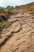 rotsachtig pad met droge struiken en mensen die op een zonnige dag in de buurt van cambara do sul naar de top van de fortaleza-kloof gaan. een klein stadje in het zuiden van Brazilië met verbazingwekkende natuurlijke toeristische attracties. foto