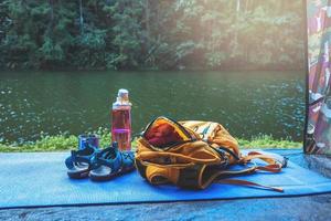 reizen natuur. reizen ontspannen. rugzak en schoenen mobiele telefoon met een travel.sun set geplaatst voor de tent camping. achtergrond van de natuur van het bergmeer. foto