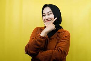 mooie jonge aziatische moslimvrouw met handen v-teken op kin, zelfverzekerd, enthousiast en vrolijk glimlachend, geïsoleerd foto