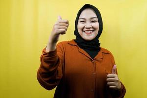 mooie jonge aziatische moslimvrouw met handen duimen omhoog, ok teken, succes, goed werk, succesteken, glimlachend zelfverzekerd, enthousiast en vrolijk, geïsoleerd foto