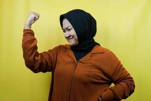 mooie aziatische jonge moslimvrouw met opgeheven spieren, geïsoleerde wapens van het sterkteteken, foto