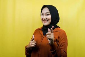 mooie jonge aziatische moslimvrouw met handen wijzend op camera, handen wijzend op publiek, camera onder ogen ziend, glimlachend zelfverzekerd, enthousiast en vrolijk, geïsoleerd foto