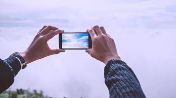 hand voor vrouwen fotografie met mobiele telefoons uitzicht op de bergen mist mist. op de bergen, de ochtendsfeer. foto