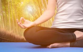 jonge vrouw blijf kalm en mediteert terwijl ze yoga beoefent in het bamboebos van de natuur. yoga en meditatie hebben goede voordelen voor de gezondheid. fotoconcept voor yogasport en een gezonde levensstijl foto