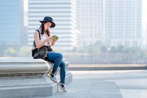mooie aziatische toeristische vrouw die reisgids leest voor het zoeken naar de locatie van toeristische bezienswaardigheden. vakantie reizen in de zomer foto