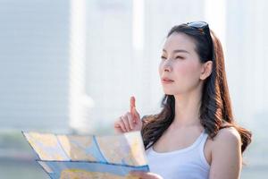 mooie aziatische toeristenvrouw die kaart bekijkt voor het zoeken van plaats van oriëntatiepunt. vakantie reizen in de zomer foto