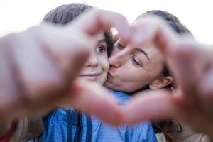 jongen met moeder gevouwen vingers in de vorm van een hart. foto