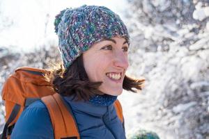 lachende vrouw met een rugzak op een achtergrond van een besneeuwd bos foto