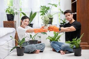 mannen en vrouwen die oranje handschoenen droegen, zaten en plantten bomen in een huis. foto