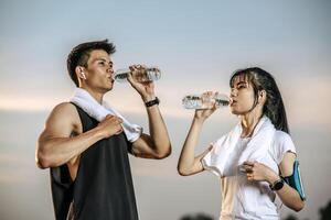 mannen en vrouwen staan om water te drinken na het sporten. foto