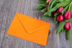 roze envelop met tulpen op een houten tafel foto