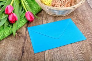 roze envelop met tulpen op een houten tafel foto