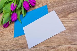blauwe envelop met tulpen op tafel foto