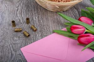 roze envelop met tulpen op een houten tafel foto
