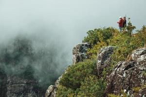 cambara do sul, brazilië - 18 juli 2019. mensen op steile rotsachtige klif bij fortaleza canyon met mist die het ravijn opkomt in de buurt van cambara do sul. een klein landelijk stadje met verbazingwekkende natuurlijke toeristische attracties. foto