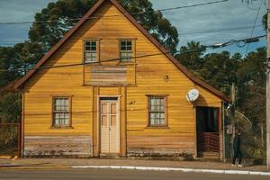 cambara do sul, brazilië - 19 juli 2019. gevel van houten oud huis en voetganger in een stenen straat bij cambara do sul. een klein landelijk stadje met verbazingwekkende natuurlijke toeristische attracties. foto