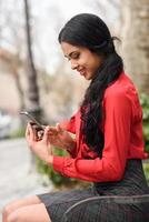 Spaanse stewardess op stedelijke achtergrond die naar haar mobiele telefoon kijkt foto